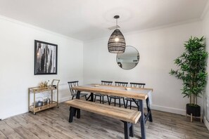 A dining area with a wooden table, chairs, a bench, a hanging light fixture, a mirror, a framed picture, and a potted plant. - Modern Scottsdale|Salt Pool + Hot Tub + Fire Pit (Scottsdale)