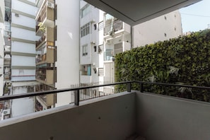A balcony with a metal railing overlooking a residential area with multiple buildings and a green hedge. - Hestia at Casa Solado (Buenos Aires)