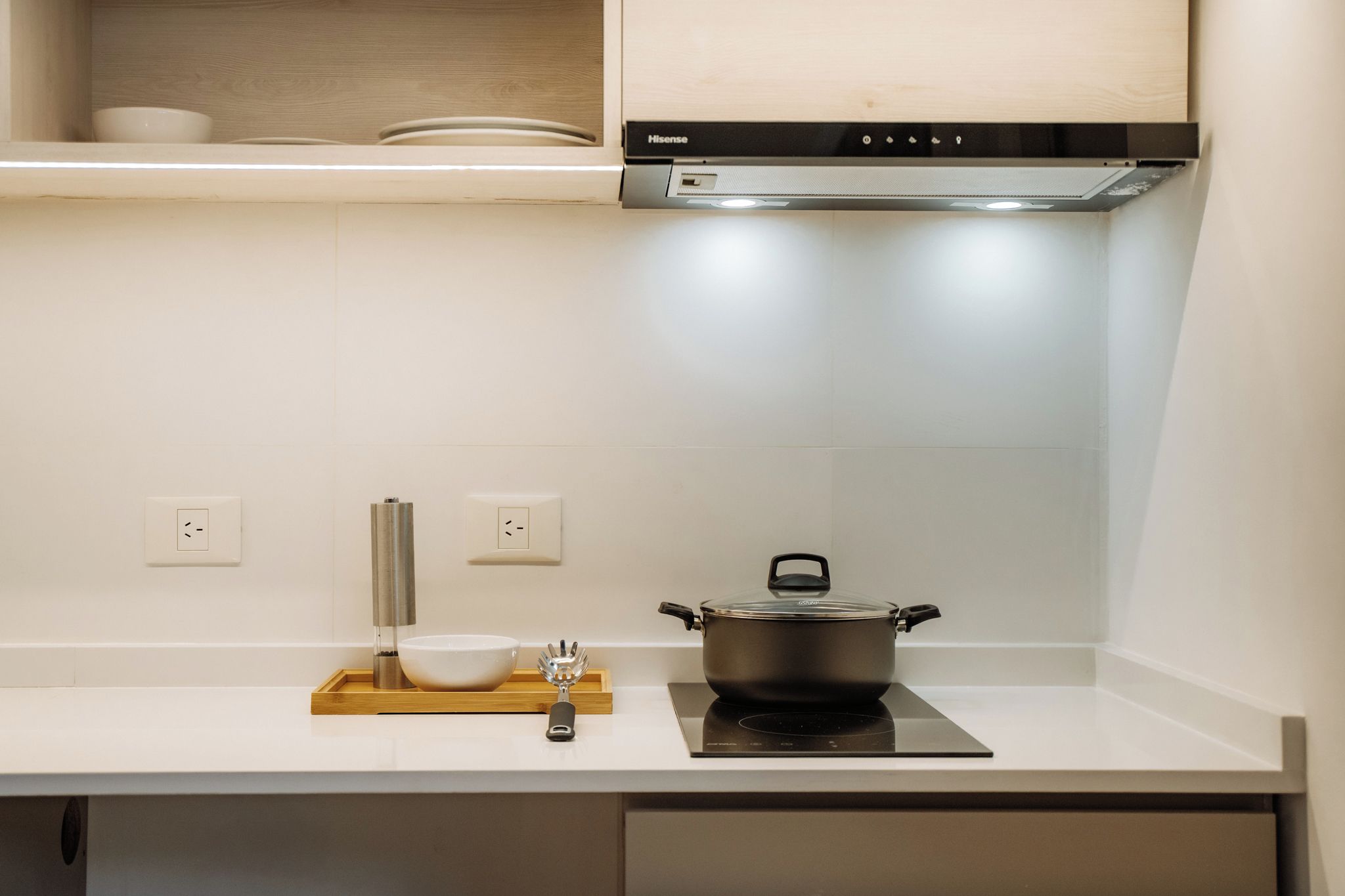 Una cocina con estufa, olla, tazón y una bandeja de madera.