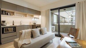 En moderne lejlighed med et tekøkken, en sofa, et spisebord og en balkon med udsigt.