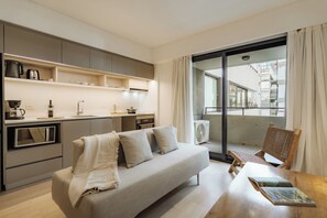 A modern apartment with a kitchenette, a sofa, a dining table, and a balcony with a view. - Hestia at Casa Solado (Buenos Aires)
