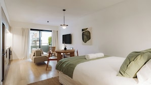 Et hotelværelse med en seng, et skrivebord, en stol, et fjernsyn og et vindue.