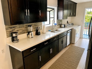 A modern kitchen with dark cabinets, a coffee maker, a blender, a toaster, and a washing machine.