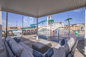 A pool area with lounge chairs, a water slide, and a view of a building with arched windows. - Heated Pool, Lazy River, Hot Tub, Pickleball, 5 EnSuites (Washington)