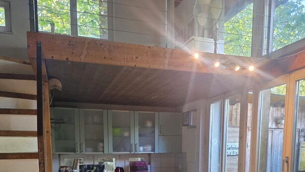 A cozy kitchen with a dining area, featuring a sofa, a dining table, and a built-in oven. - Charming garden cottage with open gallery in Erlach (Erlach)