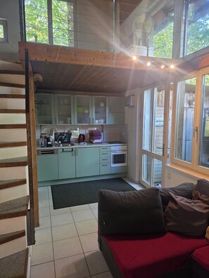 A cozy kitchen with a dining area, featuring a sofa, a dining table, and a built-in oven.