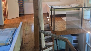 A room with a wooden ceiling, a bed, a window, a kitchen, and a staircase. - Charming garden cottage with open gallery in Erlach (Erlach)