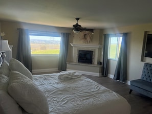 A bedroom with a large bed, a fireplace, a ceiling fan, and a view of the outdoors. - Amazing Ranch Home located on a 155 acre ranch 10 minutes from downtown Paso. (Paso Robles)