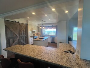 Cozinha com bancadas de granito, uma ilha grande e vista para o exterior.