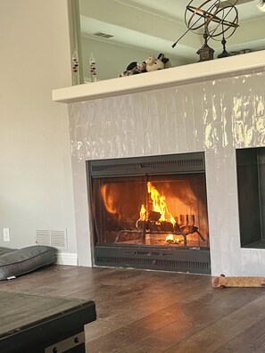 A fireplace with a fire, a mantel with decorative items, and a wooden floor. - Amazing Ranch Home located on a 155 acre ranch 10 minutes from downtown Paso. (Paso Robles)