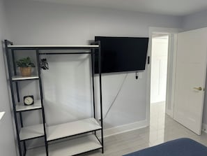 Ein Zimmer mit einer schwarzen Metallregaleinrichtung, einem an der Wand montierten Fernseher und einer Tür zu einem weiteren Raum.