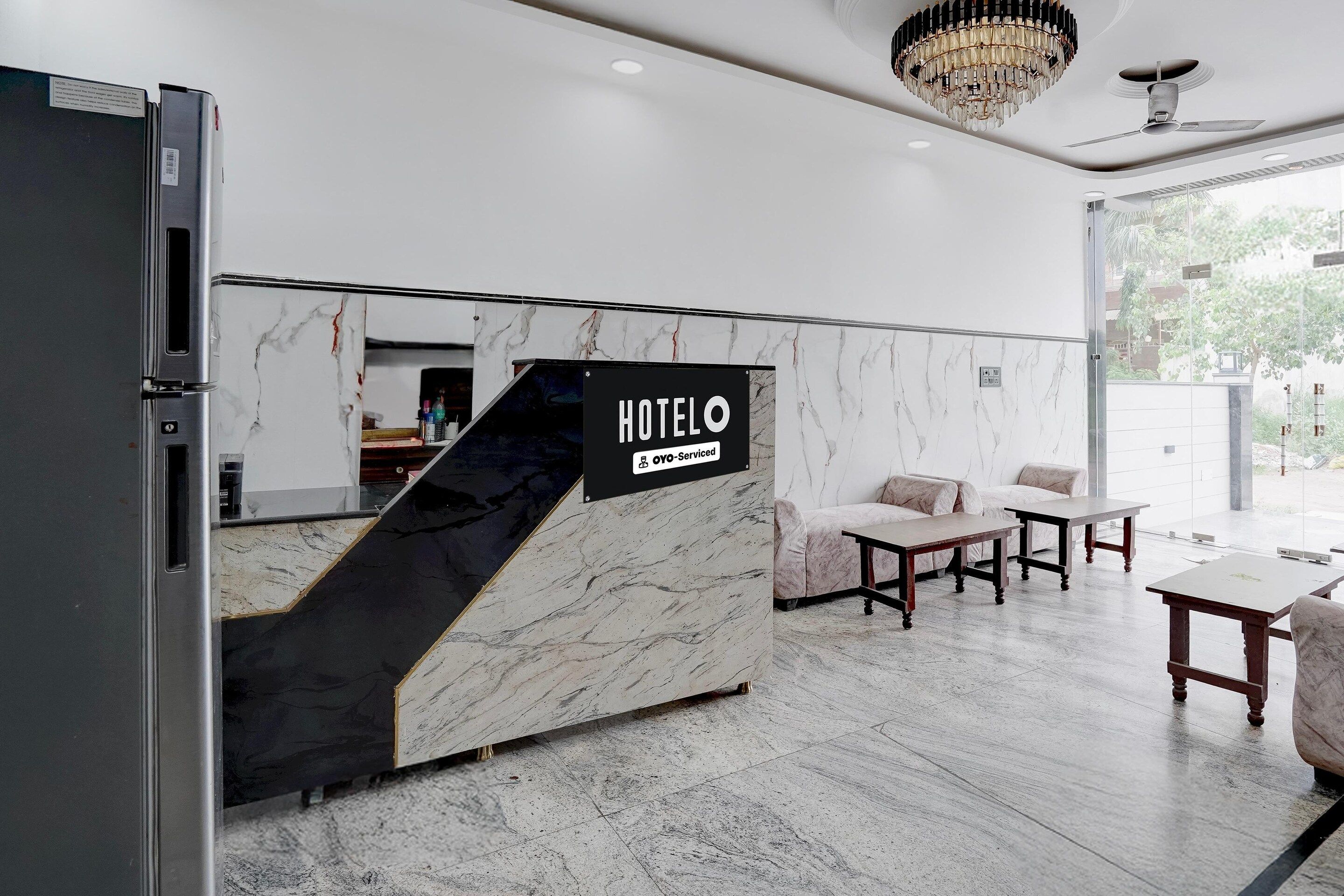 Ein Hotelrezeptionsschalter mit Marmordesign, einem Schild, das OYO ausweist, und einer Sitzecke inklusive Sofa und Tischen.