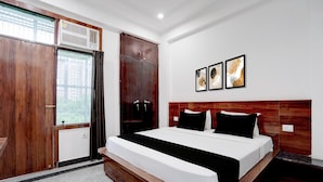 Habitación de hotel con una cama grande, armario de madera y ventana con cortinas.