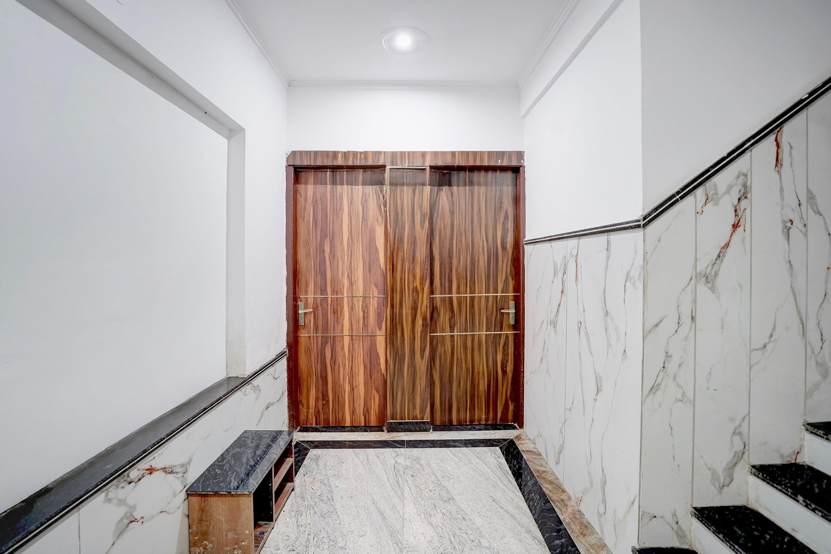 A hallway with a wooden door, marble walls, and a marble staircase.