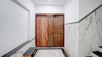A hallway with a wooden door, marble walls, and a marble staircase.