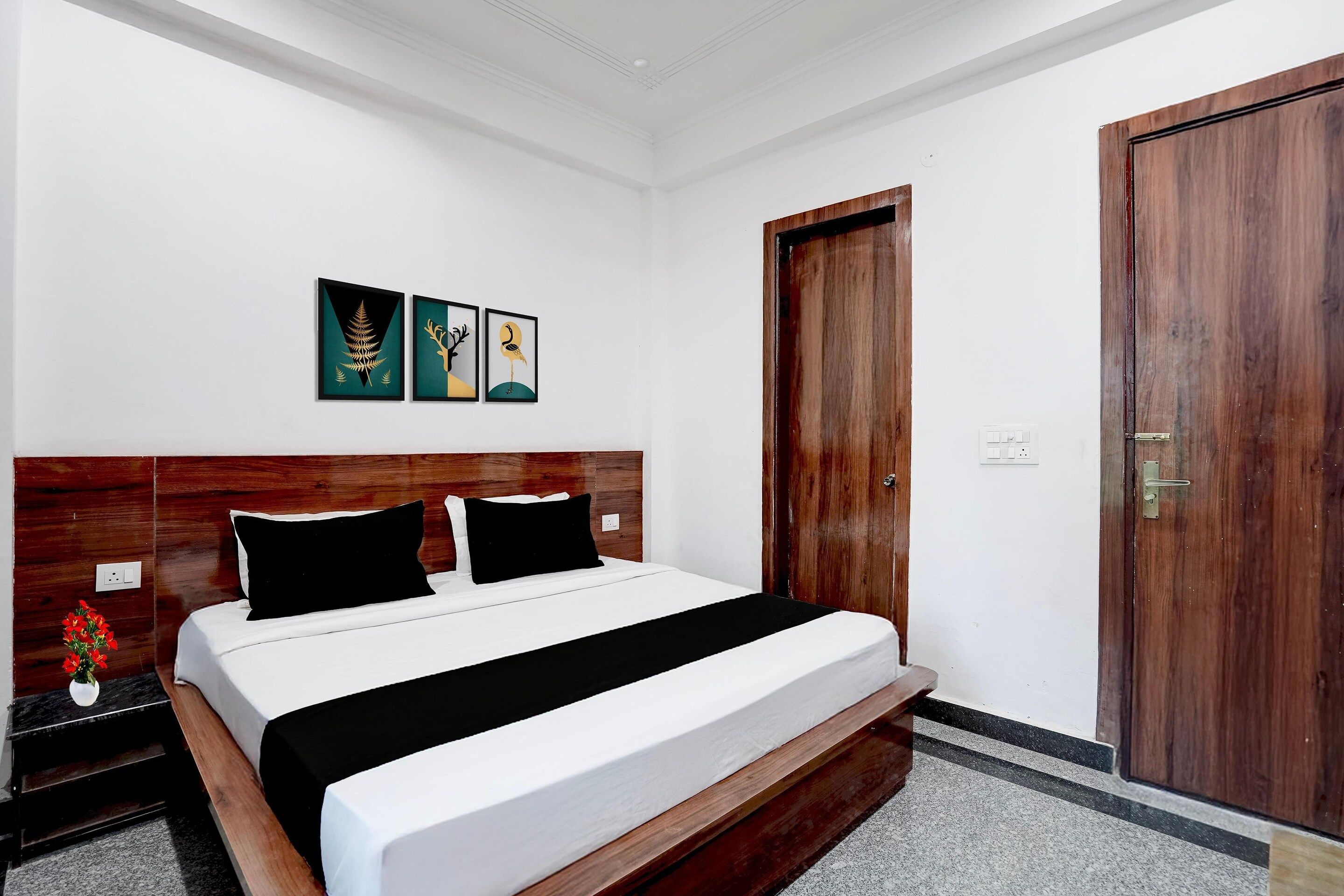Ein Hotelzimmer mit einem hölzernen Kopfteil, einem Bett mit weißer und schwarzer Bettwäsche sowie einer Tür mit einer Holzvertäfelung.