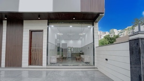 Un edificio moderno con entrada de vidrio, puerta de madera y vista del interior a través del cristal.