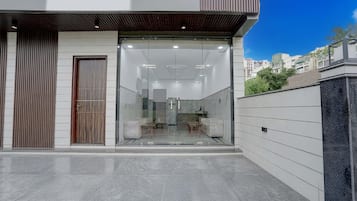 Un edificio moderno con entrada de vidrio, puerta de madera y vista del interior a través del cristal.