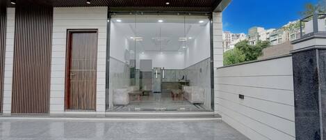 Un edificio moderno con ingresso in vetro, una porta in legno e vista dell'interno attraverso il vetro.