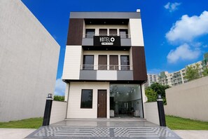 A modern hotel building with a sign that reads 'HOTEL' and 'Serviced'. - Deluxe Xponest Hotel (Greater Noida)