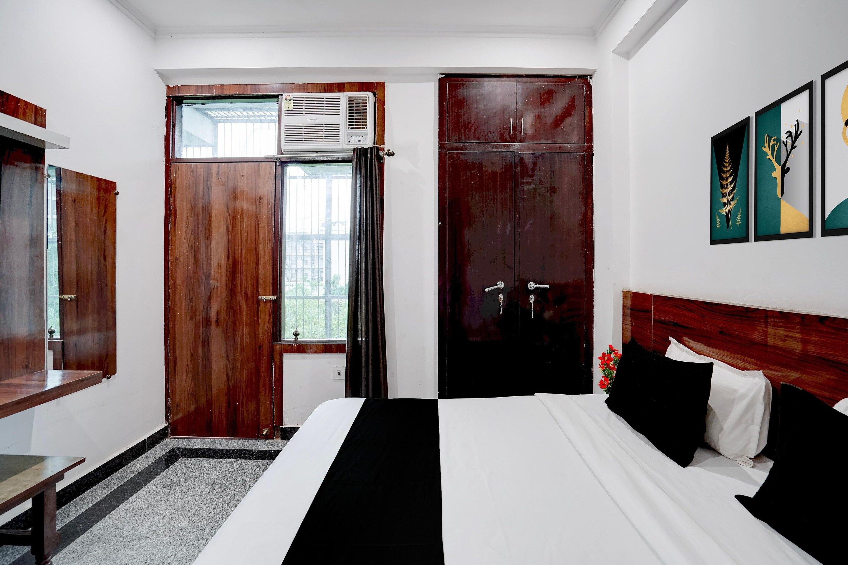 Habitación de hotel con cama, escritorio, aire acondicionado, armario y ventana con cortinas.
