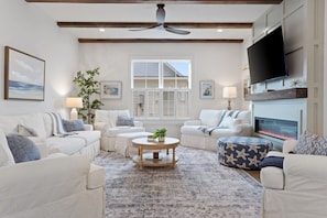 A living room with a fireplace, white sofas, a coffee table, and a television.