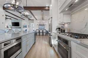 Una cocina moderna con electrodomésticos de acero inoxidable, encimera de mármol y comedor con sillas.