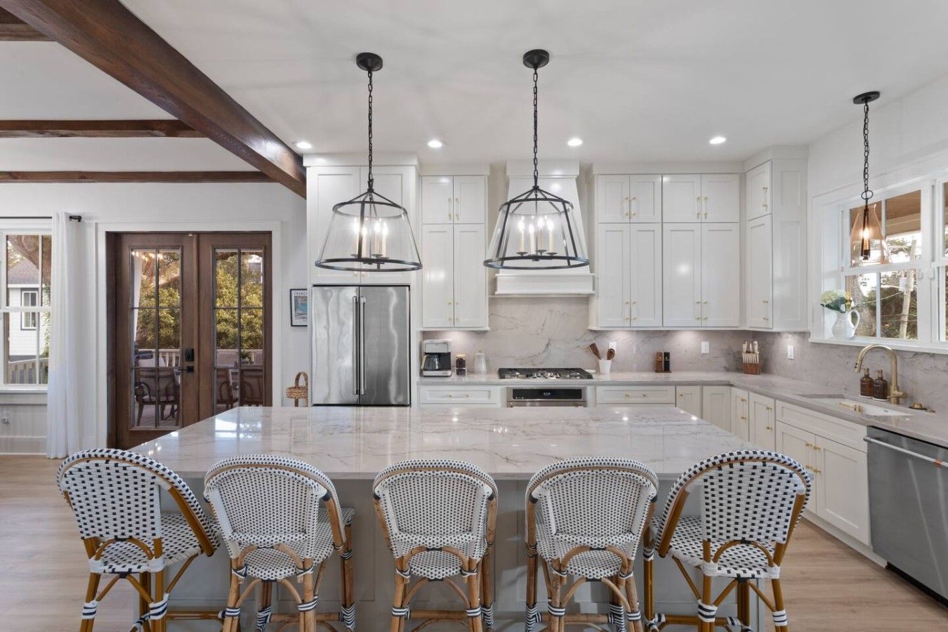 A spacious kitchen with a large island, white cabinetry, and a dining area with wicker chairs.