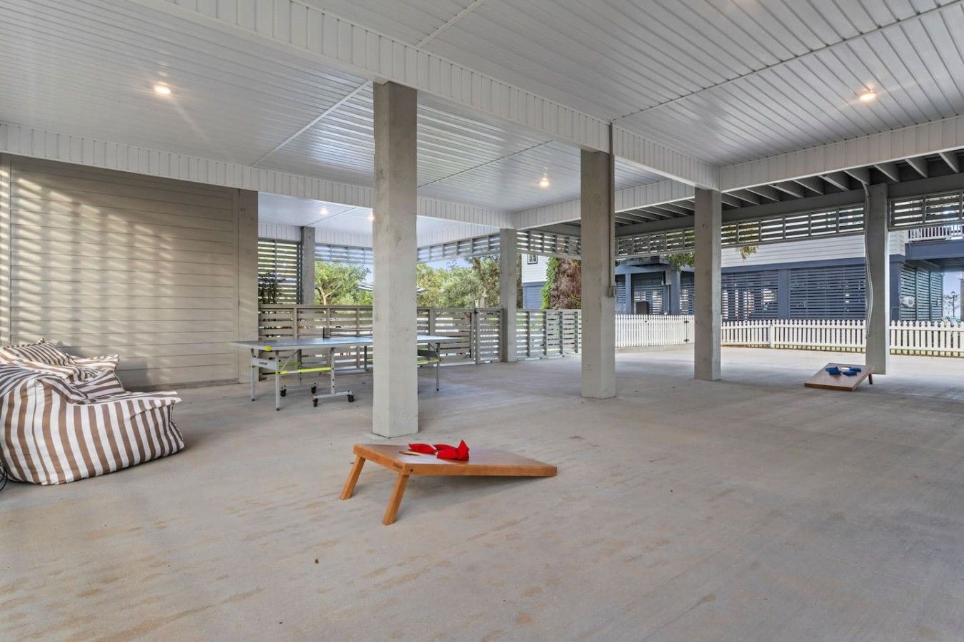 An open-plan space with high ceilings, concrete pillars, and a mix of seating areas including a sofa and tables.