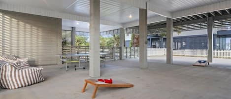 An open-plan space with high ceilings, concrete pillars, and a mix of seating areas including a sofa and tables.