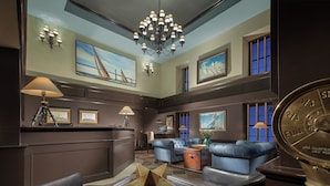 A spacious lobby with leather seating, a chandelier, framed artwork, and a clock. - Bristol Harbor Inn (Bristol)