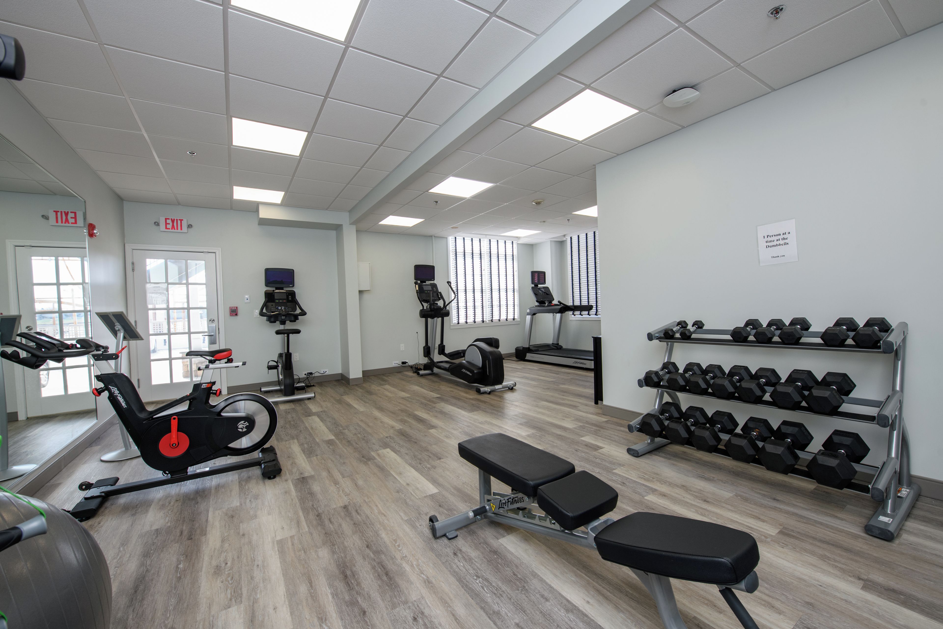 A gym with exercise equipment, a bench, and a rack of dumbbells.