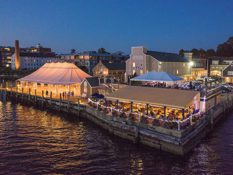 Un restaurante frente al agua con terraza al aire libre, una zona techada y un muelle que se adentra en el agua.
