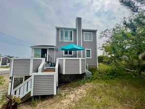 A two-story house with a covered deck and a staircase leading to the entrance.