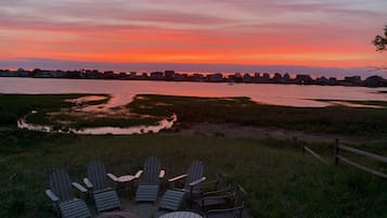 Une vue sur le coucher de soleil, avec des chaises et une table disposées dans un espace herbeux.