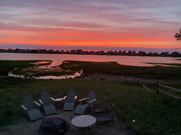 A sunset view with chairs and a table in a grassy area.