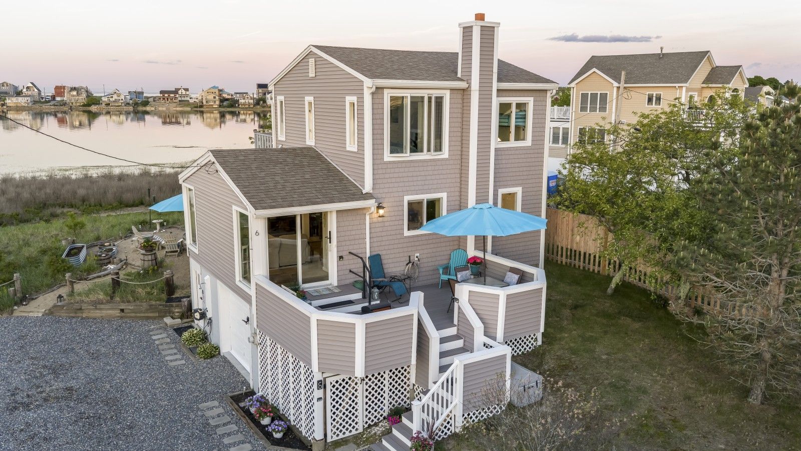 A two-story house with a deck, a covered patio, and a view of a body of water.
