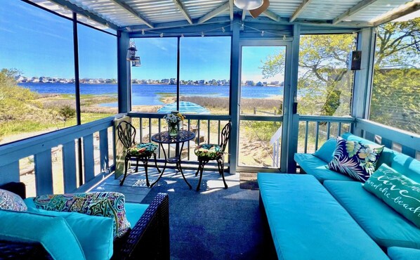 A covered outdoor seating area with a view of the water and beach.