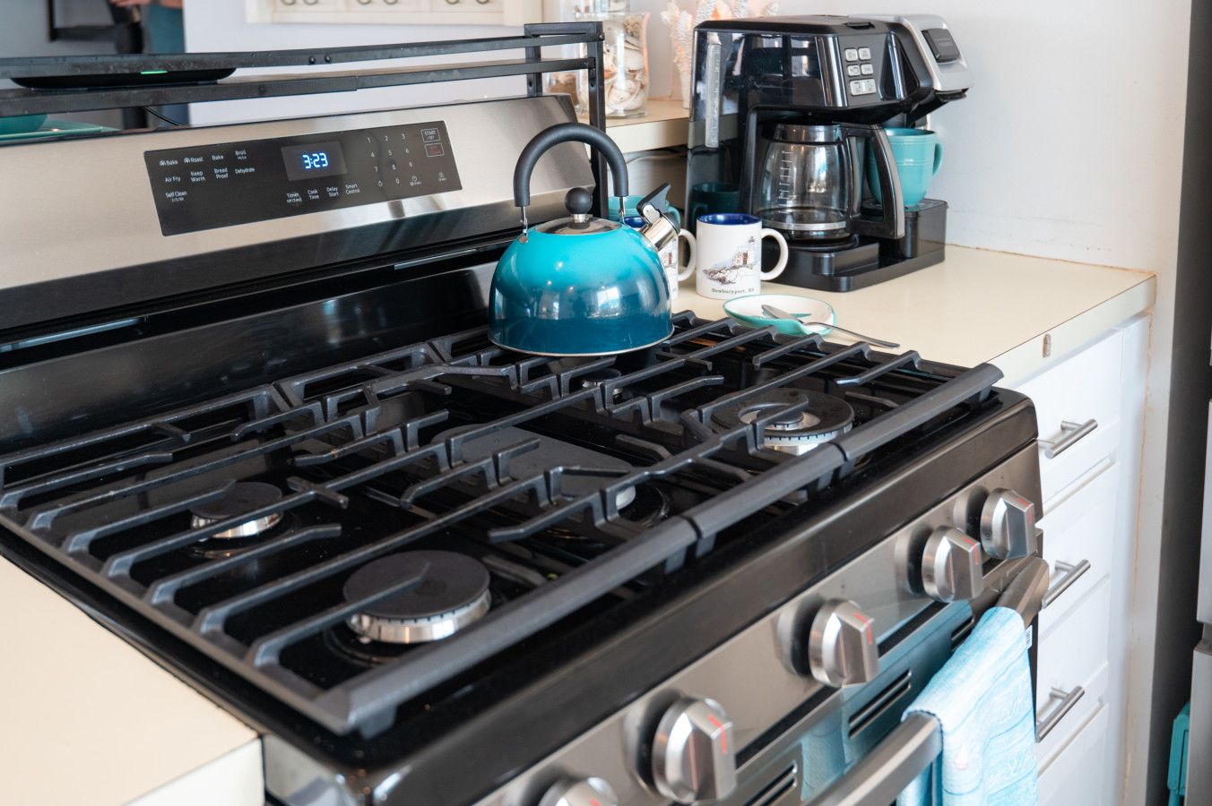 Una cocina con estufa, hervidor y cafetera.