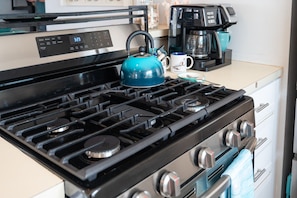 A kitchen with a stove, a kettle, and a coffee maker.