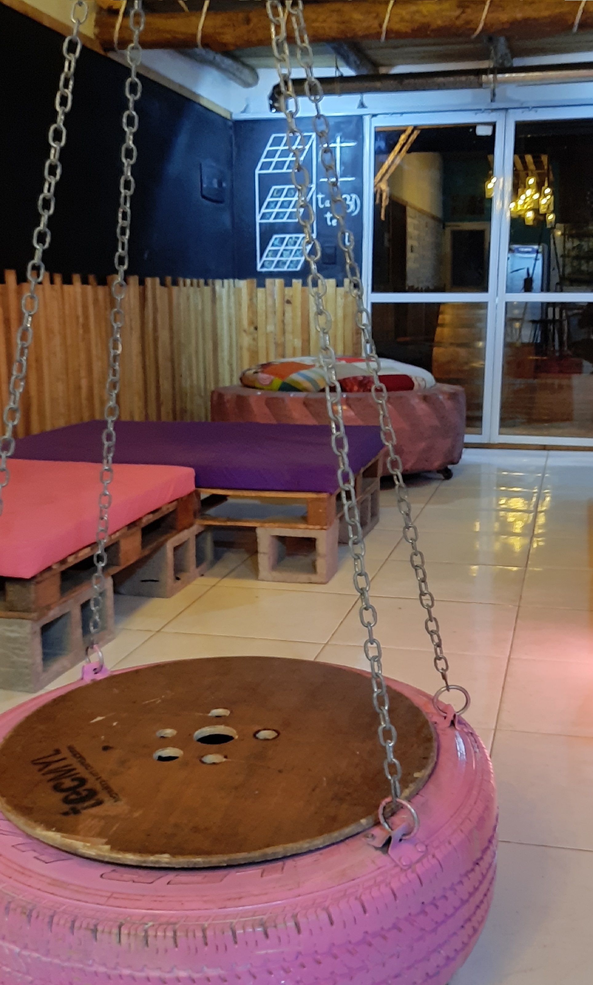 Quarto com balanço de pneu, móveis de madeira e porta de vidro que dá para o exterior.