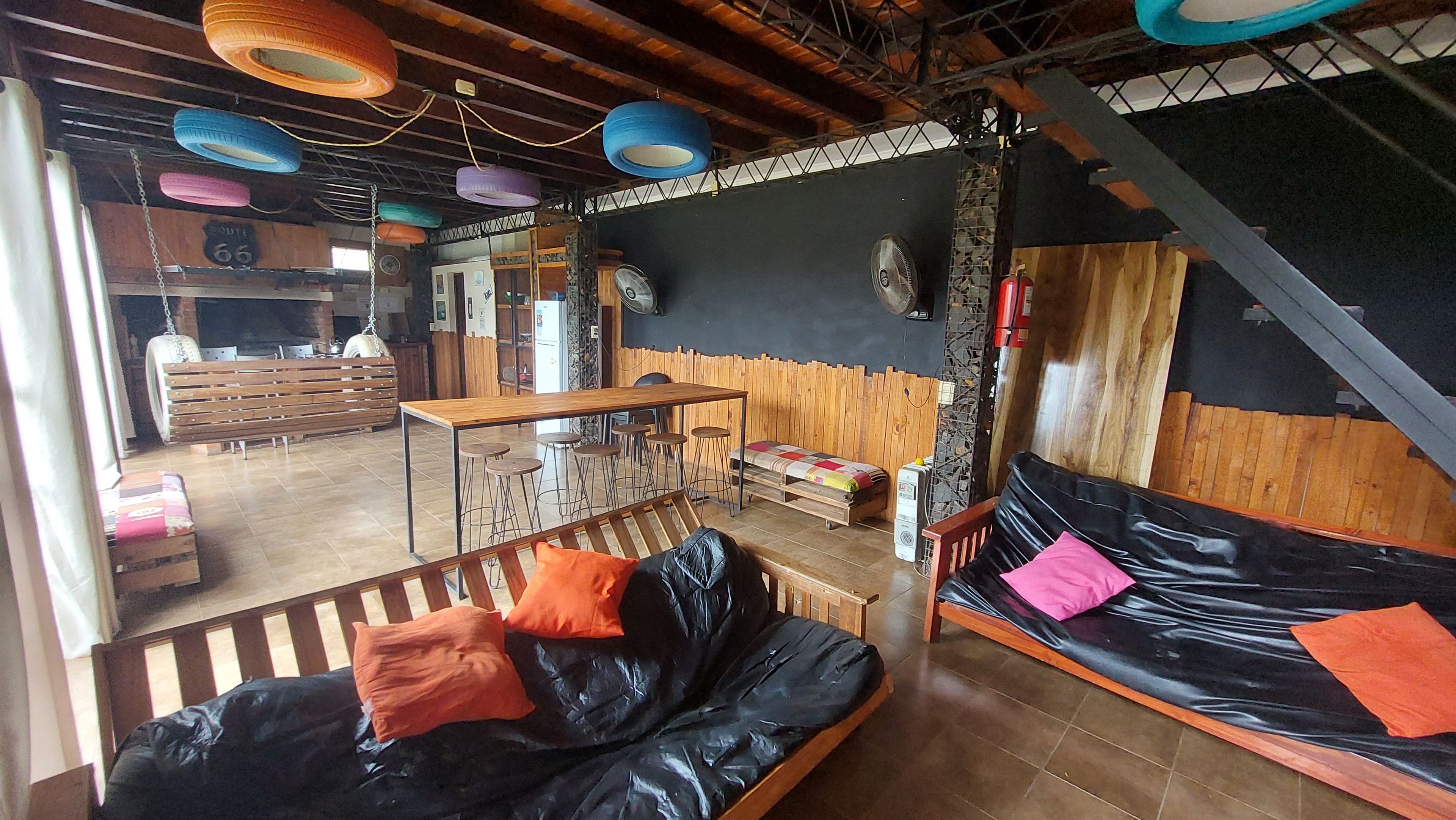 A cozy room with a black sofa, wooden benches, and a bar area with stools.