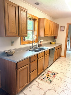A kitchen with wooden cabinets, a stainless steel sink, and a marble-patterned floor. -  Peaceful Lenoir Retreat - 3BR/2BA- Minutes from Morganton & 30 mins to Boone (Lenoir)