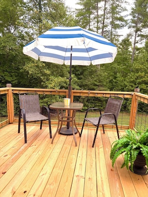 A wooden deck with a table and two chairs, an umbrella, and a potted plant. -  Peaceful Lenoir Retreat - 3BR/2BA- Minutes from Morganton & 30 mins to Boone (Lenoir)