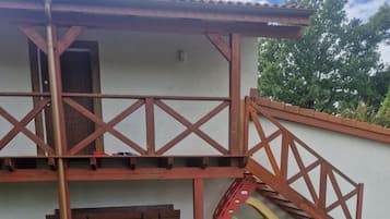 Un edificio con balcón, puerta y un tobogán pequeño.