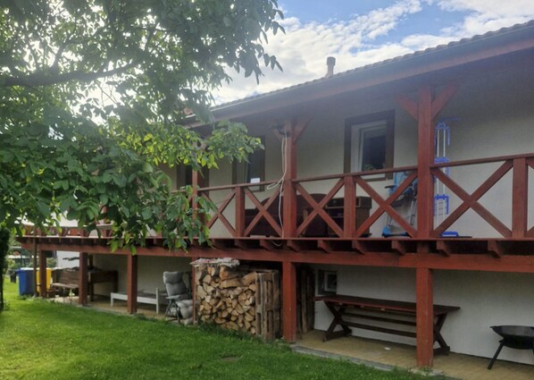 A building with a covered porch, outdoor seating, and a stack of firewood.