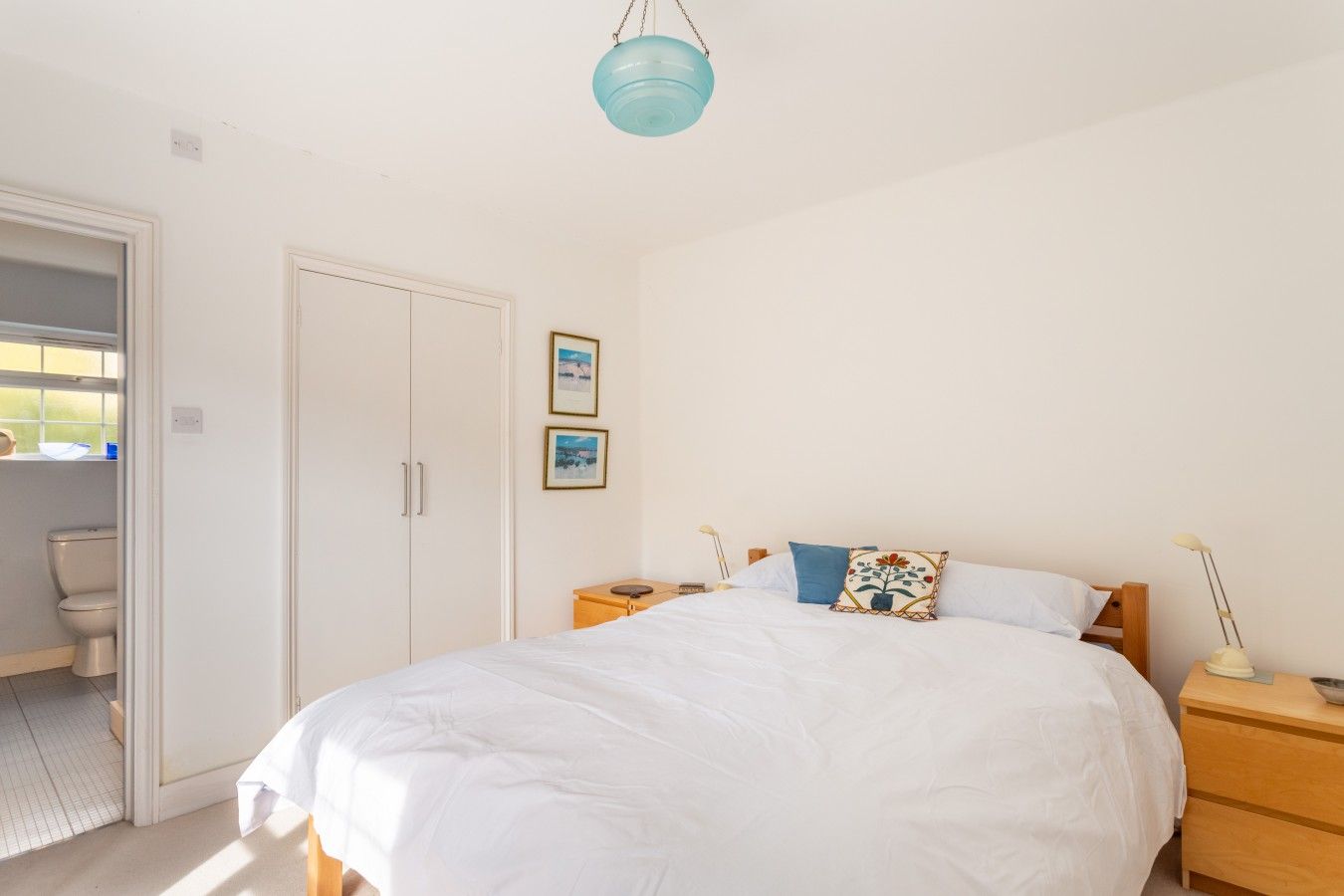 A bedroom with a bed, bedside tables, a wardrobe, and a hanging light fixture.