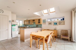 Une cuisine moderne avec des meubles en bois, un îlot central et un coin repas comprenant une table et des chaises en bois.