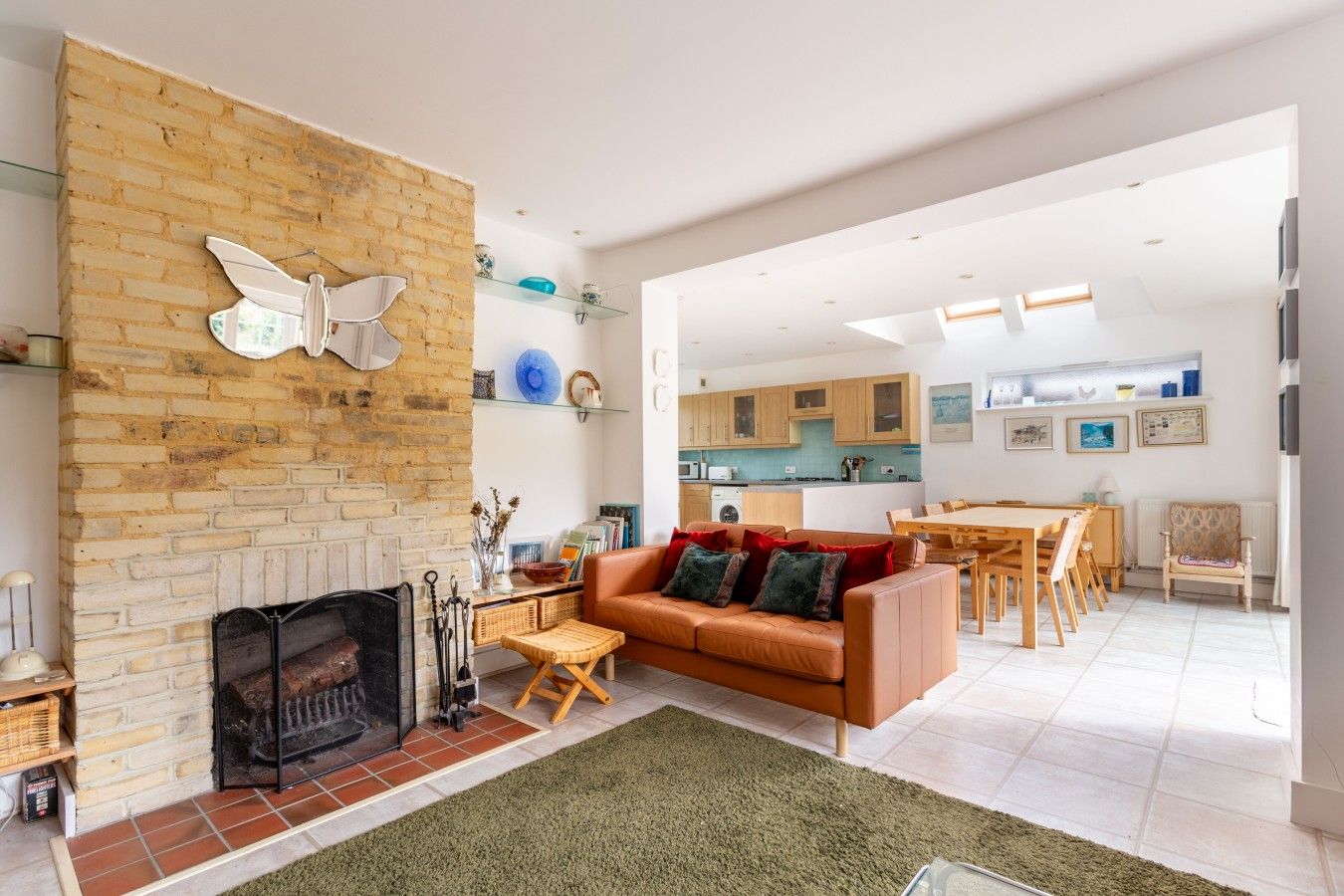A modern living room with a fireplace, a sofa, and a dining area with wooden furniture.