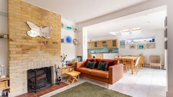 A modern living room with a fireplace, a sofa, and a dining area with wooden furniture.